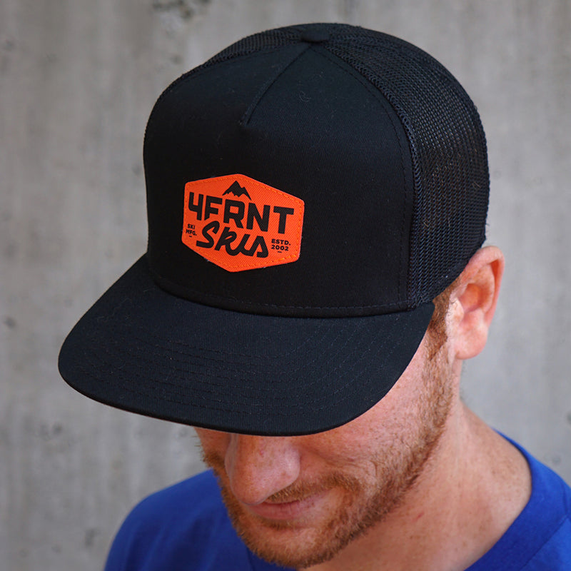MFG trucker hat with orange 4frnt badge logo pictured on a freckled, red-headed man in a blue shirt